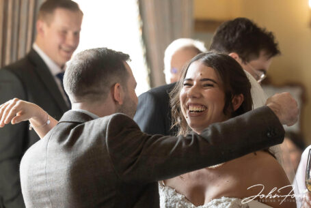 Wedding Photographer at Kilworth House in Leicester. Eleanor, the bride, being hugged by her wedding guests.