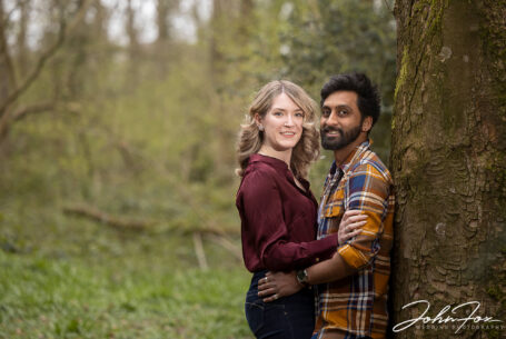 Woodland pre-wedding shoot: relaxed image of the bride and groom Isobel and Roshan holding each other while leaning against a tree