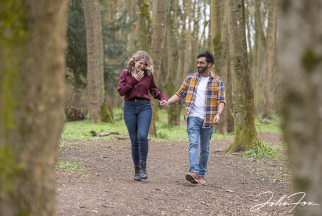 Woodland pre-wedding shoot natural image of Isobel and Roshan walking and joking