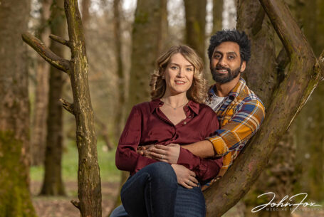 Pre-wedding and wedding photography Warwickshire. Isobel and Roshan sitting on a tree in local woodland.