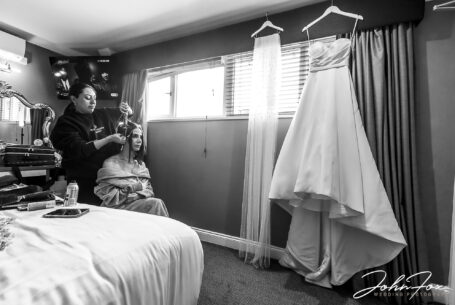 Figan's bridal preparations with her wedding dress hanging up in front of her while she has her hair styled