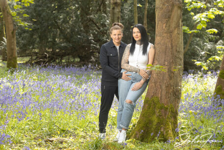 Jody and Beth’s Pre-Wedding Shoot in Rugby. The happy couple-to-be leaning against a tree surrounded by bluebells.