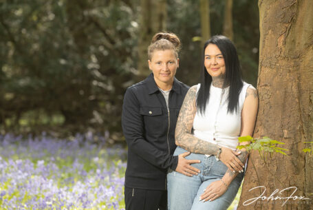 Pre-wedding shoot in bluebell woodland. Image of Jody and Beth smiling warmly at the camera.