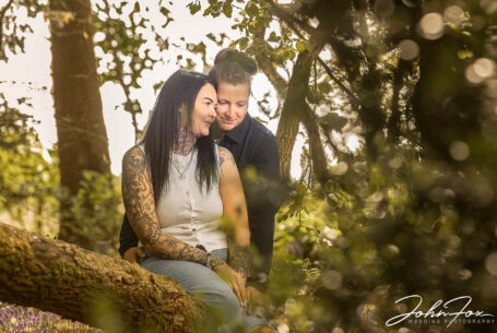 The happy couple-to-be leaning in close to each other in Warwickshire woodland.