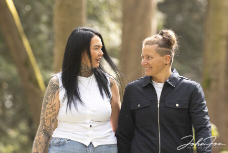 Jody and Beth hand-in-hand walking in beautiful Warwickshire woodland. Pre-Wedding Shoot in Rugby by John Fox.