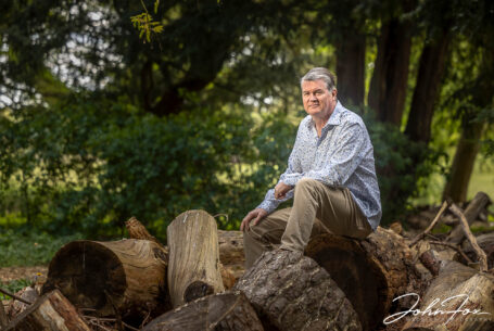 Pre-wedding shoot at Chicheley Hall. The groom-to-be, Craig, sitting on logs. Wedding Photographer in Buckinghamshire, John Fox.