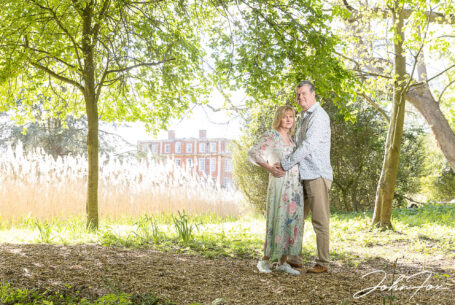 Pre-wedding image at Chicheley Hall of the happy couple in the gardens of the venue with the sunlight on reeds in the background. Wedding Photographer in Buckinghamshire, John Fox.