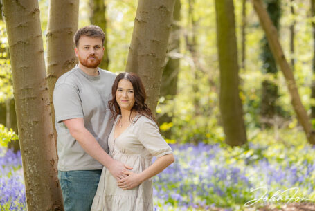 An image of the happy couple, Rikki and Jack, leaning against a tree. Pre-wedding shoot in Warwickshire woodland. Wedding Photographer in the West Midlands, John Fox.