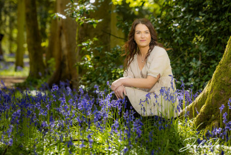 Pre-wedding shoot in Warwickshire woodland. An image of the bride-to-be, Rikki, sitting amongst the bluebells. Wedding Photographer in the West Midlands, John Fox.