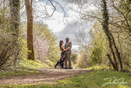 Pre-wedding shoot in parkland in Milton Keynes. Figan and Philip holding each other close whilst stood amongst the trees.