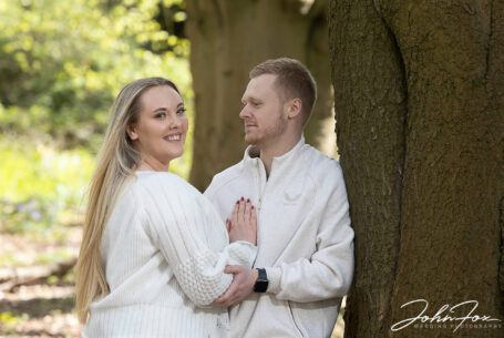 Pre-wedding shoot at Mapperley Reservoir's woodland area with Tia and Kieran, holding each other by a tree. John Fox: wedding photographer covering Nottinghamshire